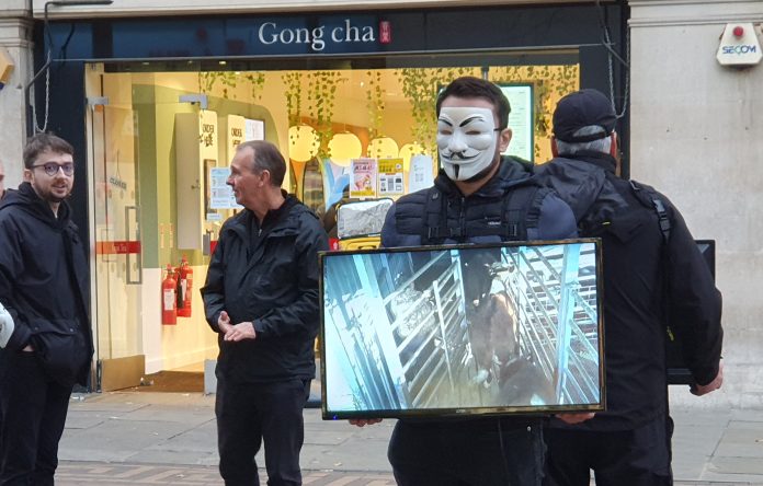 People stopping in the street to watch Anonymous for the Voiceless' screen